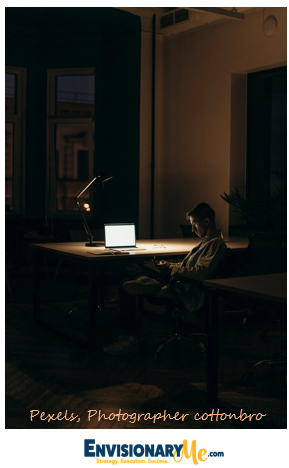 Image of Entrepreneur at work early morning or late at night at his desk in home office EnvisionaryMe
