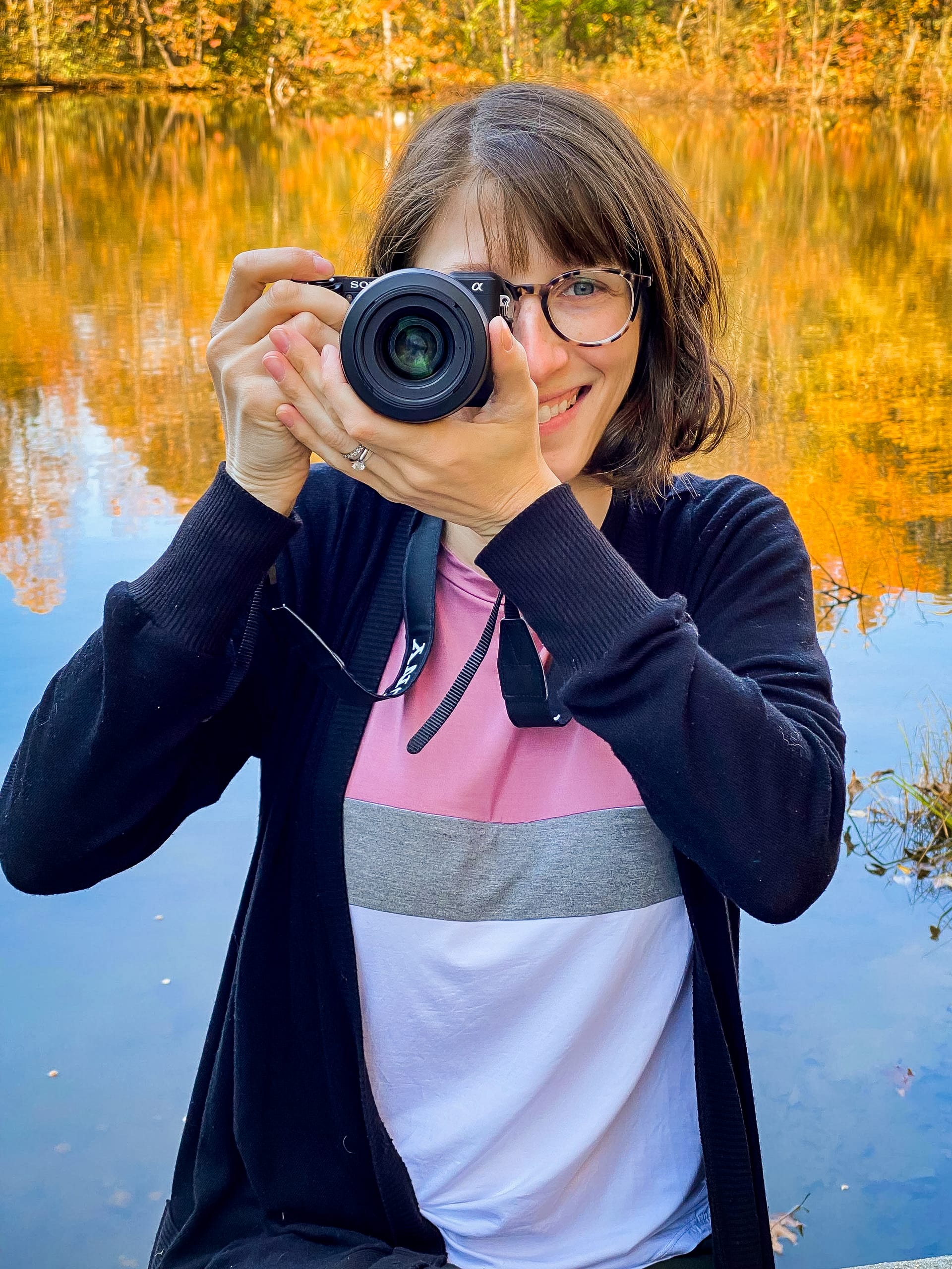 female Entrepreneur holding camera ready to shoot at the lake