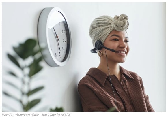 Female entrepreneur on headset - phone call with clock on the wall
